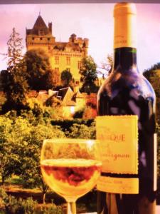 een fles wijn en een glas wijn met een kasteel bij Maison de Montfort in Vitrac