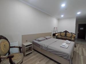 a bedroom with a bed and a chair in it at Hotel VENUS in Tbilisi City