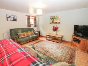 a living room with a couch and a tv at Horse Shoe Cottage in Bradley in the Moors