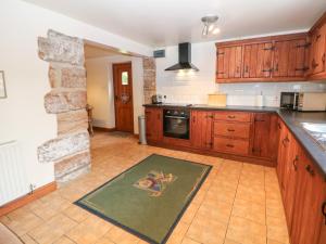 a kitchen with wooden cabinets and a stone fireplace at Horse Shoe Cottage in Bradley in the Moors