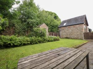 a wooden bench sitting in a yard next to a building at Horse Shoe Cottage in Bradley in the Moors