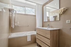 a bathroom with a tub and a sink and a mirror at White Waters Hotel in Machico