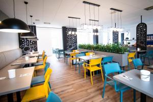 a restaurant with yellow and blue chairs and tables at Taste Hotel Jettingen in Jettingen-Scheppach