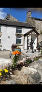 a house with a bench and flowers in front of it at Brock cottage Tideswell newly modernised in heart of Peak District National Park in Tideswell +8 photos