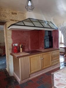 a kitchen with wooden cabinets and a stove top oven at chambre pour 3 in Osmanville