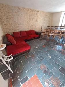 a living room with a red couch and a table and chairs at chambre pour 3 in Osmanville