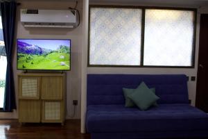 un salon avec un canapé bleu et une télévision à écran plat dans l'établissement Urban Oasis Studio with Bathtub & Garden - Vientiane Centre, à Vientiane