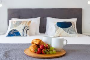 メドゥリンにあるLuxury apartment near the beachのベッドの上にフルーツとクロワッサンとカップが置かれたトレイ