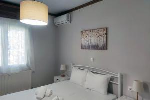 a white bedroom with a bed with white pillows at Nikis House in Keramoti