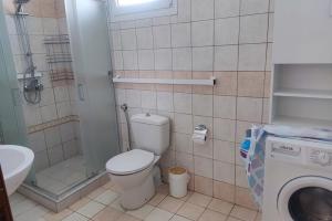a bathroom with a toilet and a shower and a washing machine at Nikis House in Keramoti +10 photos