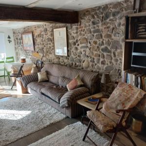 a living room with a couch and a stone wall at Apartamento Kuttun Bermeo in Bermeo +16 photos