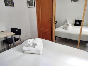 a bedroom with a bed with towels and a mirror at La Habitación de Santa Eulalia habitación privada in Hospitalet de Llobregat
