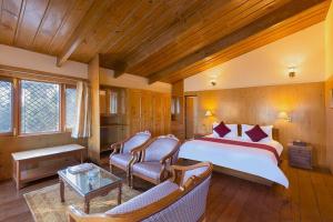 une chambre avec un grand lit et deux chaises dans l'établissement Lions Den Estate 7 BD Ramgarh serviced Villa BBQ, à Rāmgarh