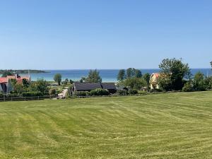 a field of green grass with houses and the ocean at Klinta Seaview Cabin ensuite in Köpingsvik