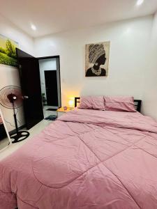 a bedroom with a large bed with a pink comforter at Rai Staycation in Sampong