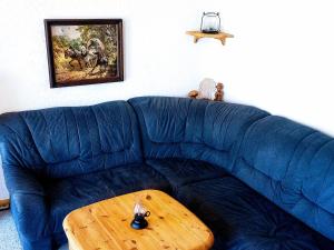 ein blaues Sofa mit einem Holztisch im Wohnzimmer in der Unterkunft Hexenstube Morgana WLAN, tolles Bad und toller Balkon in Braunlage