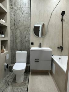 a bathroom with a toilet and a sink and a mirror at Уютная квартира 5 минут от Барыс арены in Astana