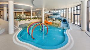 a swimming pool with a slide in a building at Apartamenty Tukan- Polanki Aqua - Holiday City in Kołobrzeg