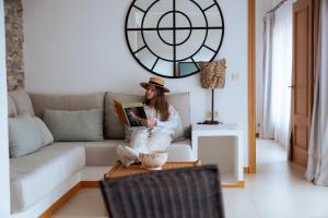 a woman sitting on a couch reading a book at BYPILLOW Cap Sa Sal in Begur