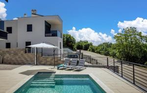 a swimming pool with two chairs and an umbrella next to a house at Villa Aura by Villas Guide in Urinj