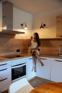 a woman sitting on the counter of a kitchen at BYPILLOW Cap Sa Sal in Begur