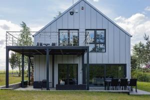 a white house with black windows and chairs at Glow Apartments - Dom Ostoja Rekownica, Kaszuby na 10 osób z sauną i balią in Będomin
