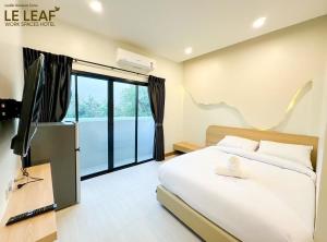 una camera da letto con un letto e una TV a schermo piatto di Leleaf Work Spaces Hotel - เลอลีฟ เวิร์คสเปซ โฮเทล a Sakon Nakhon