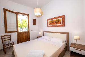 a bedroom with a bed and a chair and a window at CasaVacanzeAurora in San Vito lo Capo