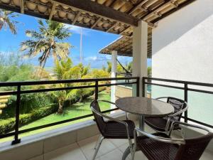 a table and chairs on a balcony with a view of the ocean at Bangalôs de Peroba in Maragogi