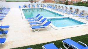 a swimming pool with blue lounge chairs next to it at Hotel Monte Lírio in Espinho