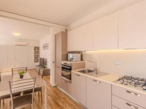 a kitchen with white cabinets and a table and chairs at Apartment Calicantus - Nespolo by Interhome in Dro