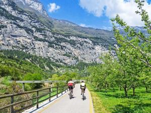 two people riding bikes on a road with mountains at Apartment Calicantus - Nespolo by Interhome in Dro