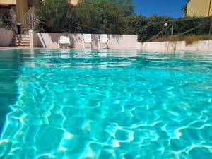 ein Pool mit blauem Wasser und Stühlen darin in der Unterkunft Apartment Mara by Interhome in Badesi