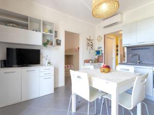 eine Küche mit weißen Schränken sowie einem weißen Tisch und Stühlen in der Unterkunft Apartment Mara by Interhome in Badesi