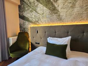a bedroom with a bed and a green chair at Hotel Reine Victoria in St. Moritz +51 photos