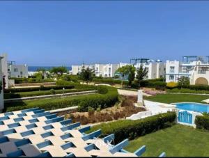 a row of chairs and a swimming pool in a resort at Chalet at Mountain View Ras El Hekma in Ras Elhekma
