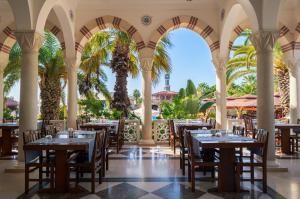 a restaurant with tables and chairs and palm trees at Ali Bey Club & Park in Kizilagac