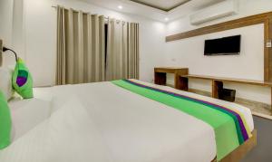 a bedroom with a white bed and a television at Treebo The Kings Plaza in New Delhi +36 photos