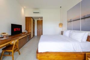 サヌールにあるBraya livingのベッドとテレビ付きの机のある寝室