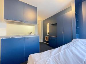 a room with blue cabinets and a bed and a sink at Allihoop Ängby Aces in Stockholm +8 photos