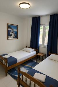 a bedroom with two beds and blue curtains at Apartments Danilo in Herceg-Novi +13 photos