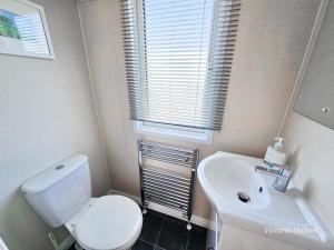 a bathroom with a white toilet and a sink at Sea views at Serenity! in Truro +21 photos