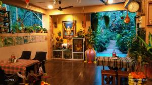 a restaurant with plants and tables and a clock on the wall at Anandi Villa Homestay in Adi