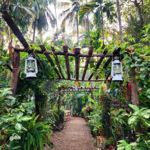 a garden with a wooden arch and lights at Anandi Villa Homestay in Adi