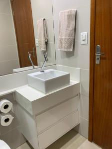 a white bathroom with a sink and a mirror at Casa moderna e confortável 2andar in Leopoldina