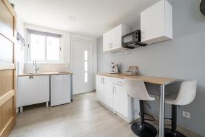 a kitchen with white cabinets and a table with chairs at Coquet studio in Port-de-Bouc