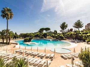 duży basen z krzesłami i palmami w obiekcie Appartement 2 Pièces avec Piscine et Parking - FR-1-504-663 w miejscowości Saint-Raphaël +4 zdjęcia