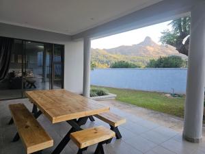 a wooden table and benches on a patio with a mountain at La Dolce Vita in Lobamba