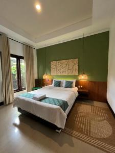 a bedroom with a large bed with a green wall at Villa Padi Cangkringan in Sleman +89 photos