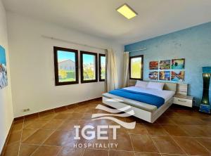 a bedroom with a bed with blue walls and windows at Standalone with private pool in Marassi Victoria in El Alamein